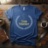 Blue t-shirt with gold "You Matter" text inside a white laurel wreath and a small constellation graphic