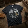 Humorous "You smell COW POOP I SMELL MONEY" text design with cow and money graphics on a dark t-shirt
