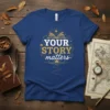 Your Story Matters quote in gold and white text on a blue t-shirt, featuring an open book graphic and celestial