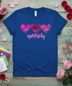 Blue t-shirt with the text "#galentines day" in pink neon script and three abstract hearts above it